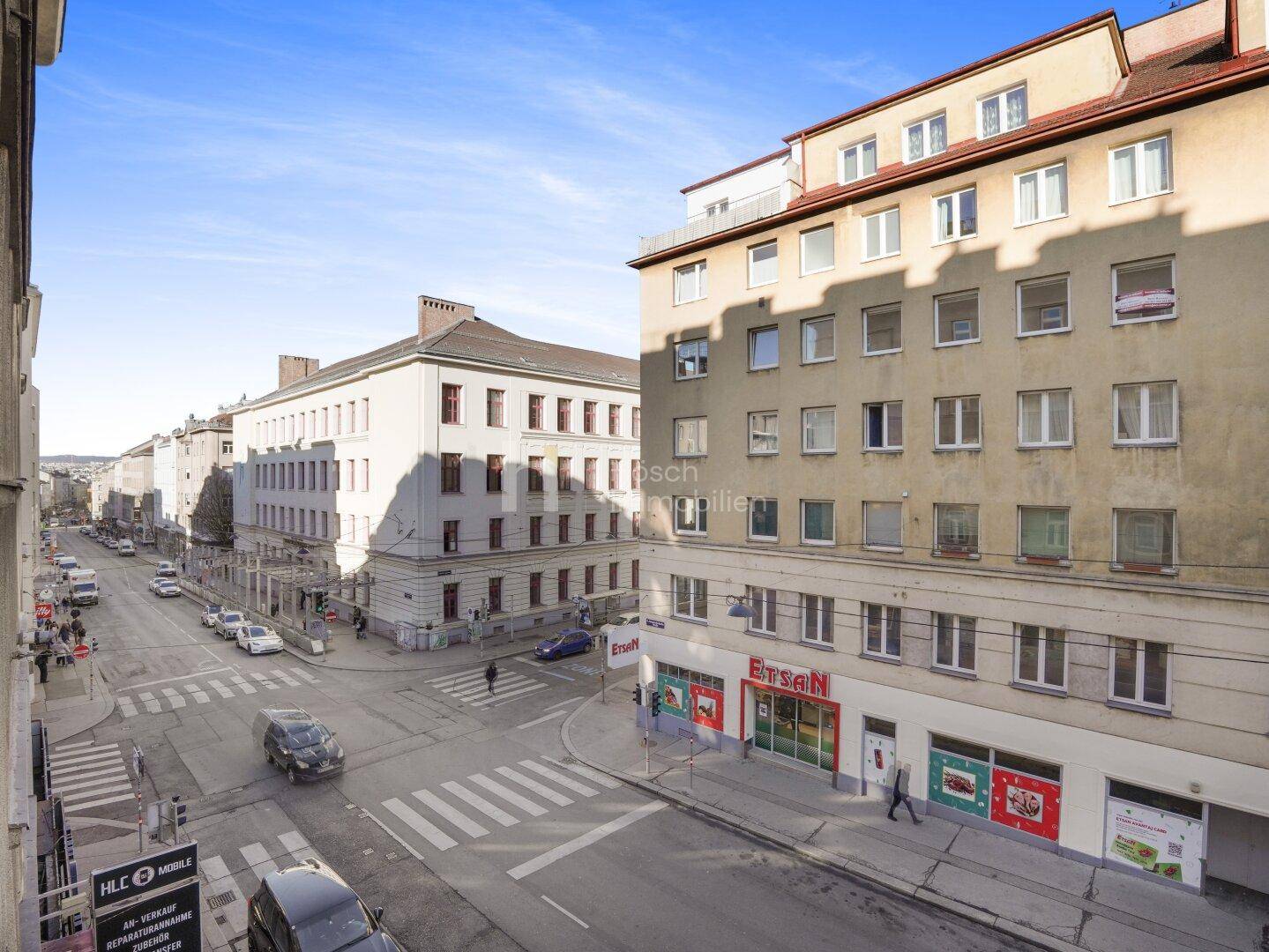 Blick auf eine belebte Stadtstraße mit Gebäuden und Geschäften unter blauem Himmel.
