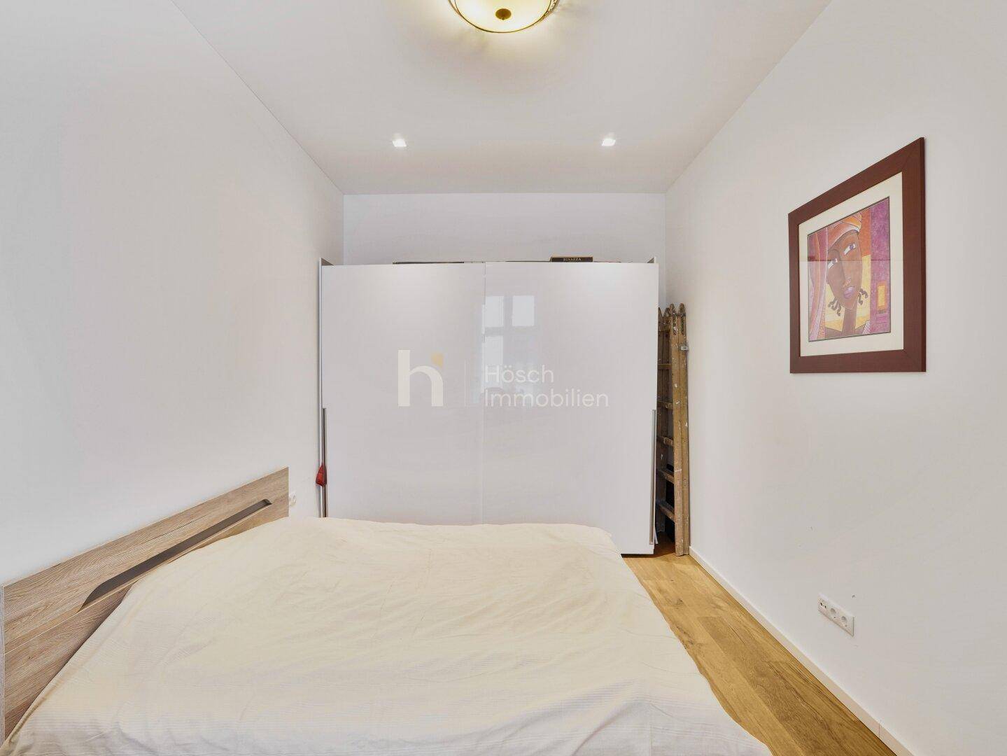 Gemütliches Schlafzimmer mit Holzbettrahmen und großem weißen Kleiderschrank.