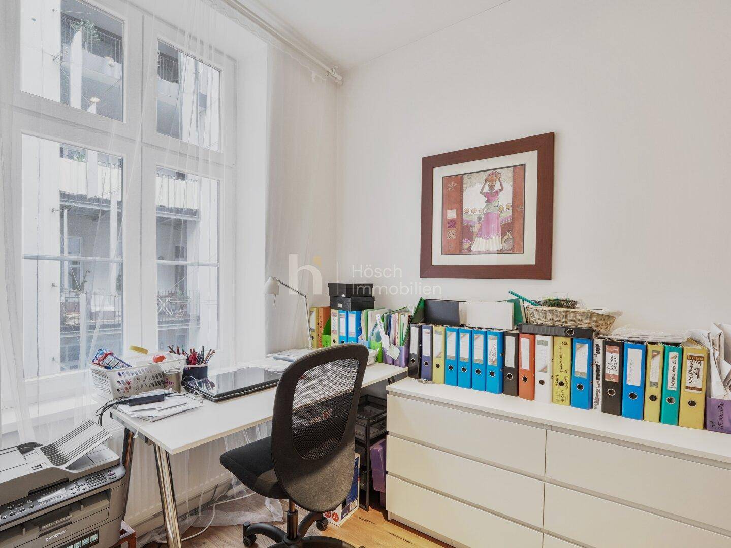 Funktionales Arbeitszimmer mit Schreibtisch, Bürostuhl und Blick nach draußen durch das Fenster.