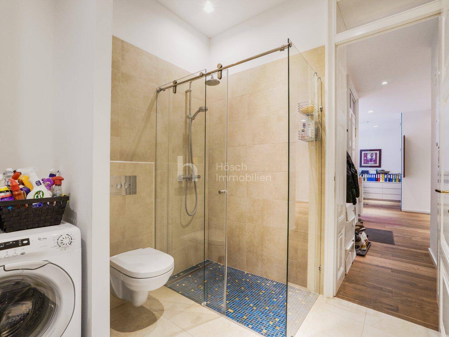 Helles Badezimmer mit großer Glasdusche, Wand-WC und Waschmaschine.