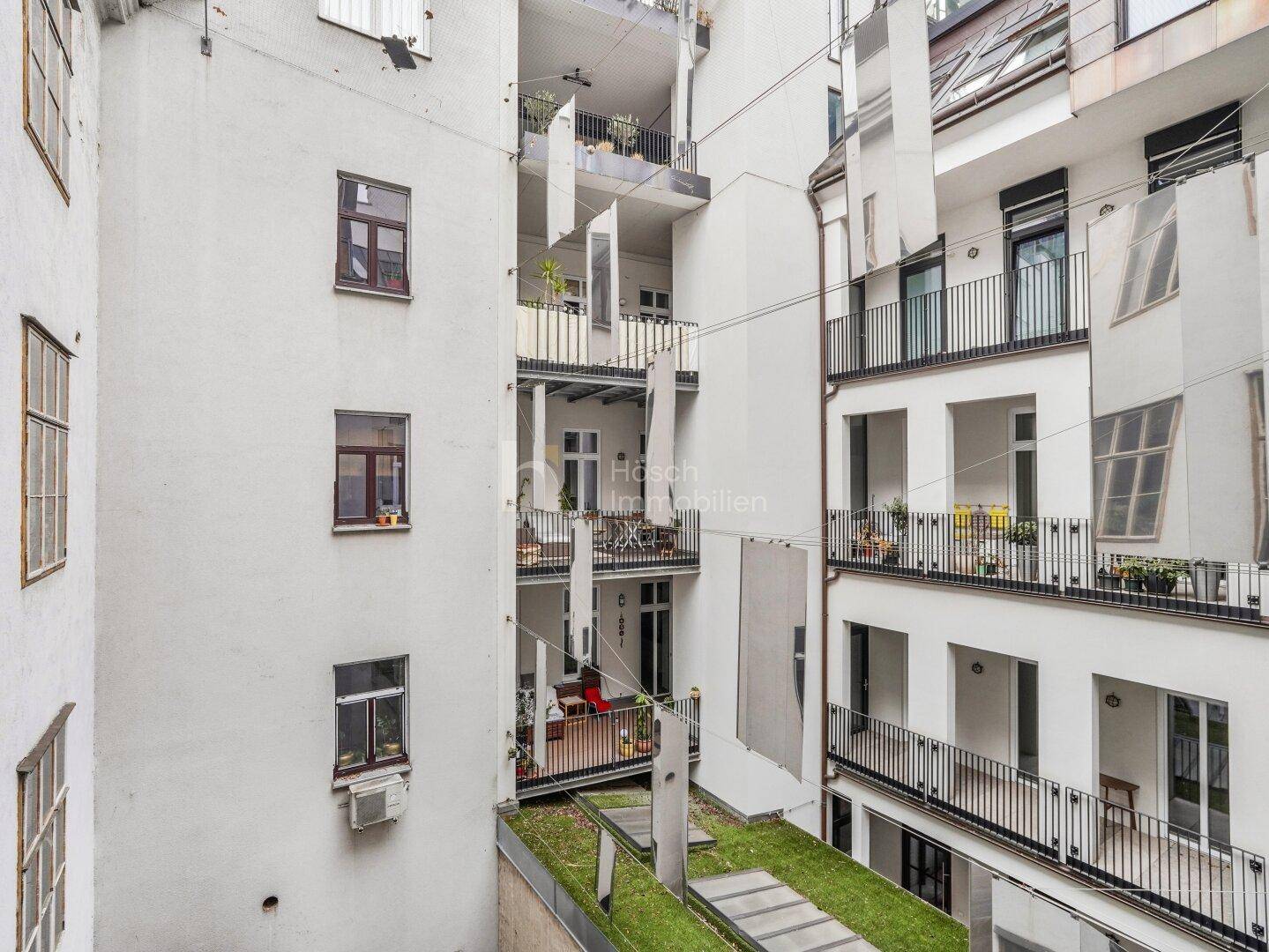 Blick in den begrünten Innenhof mit mehreren Balkonen und modernen Fassadenelementen.
