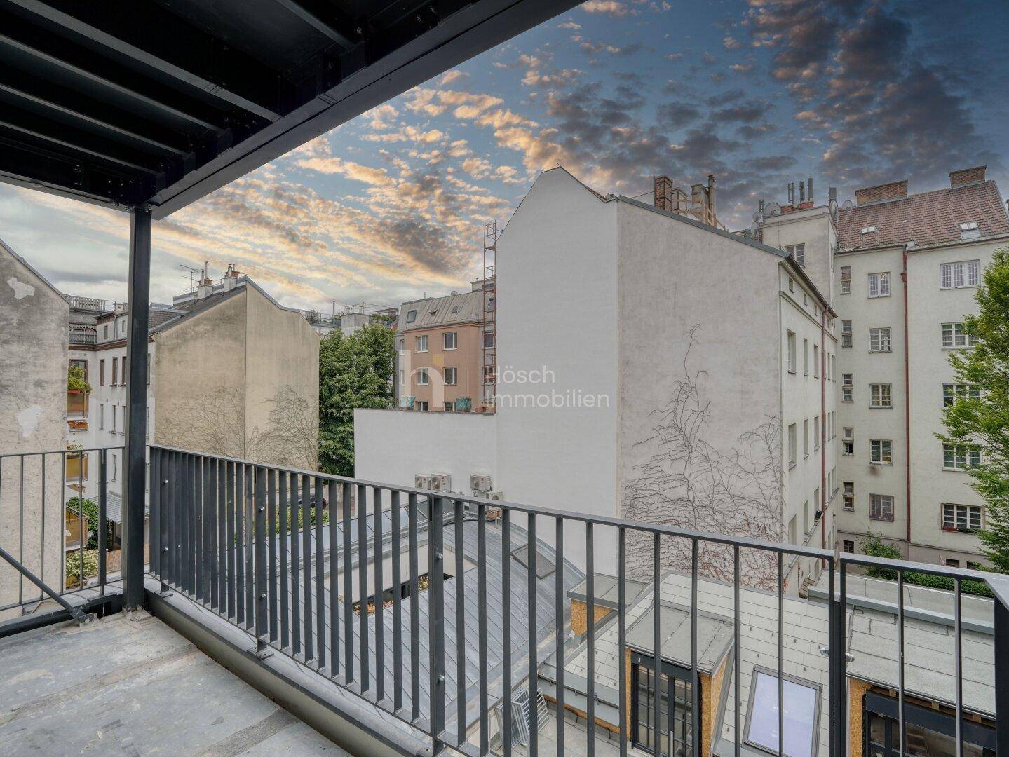 Balkon mit weitem Blick über die Dächer der Stadt und umliegende Gebäude, unter dramatischem Himmel.