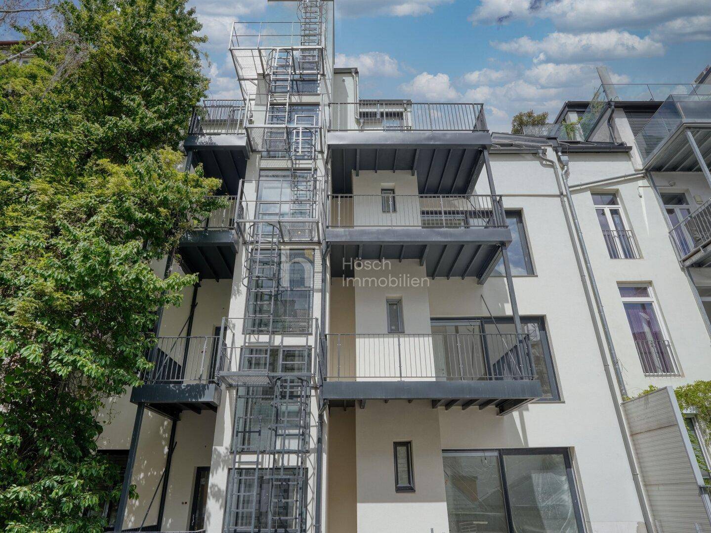 Ansicht der modernen Gebäudefassade mit externem Aufzug und Balkonen, architektonisch ansprechend.