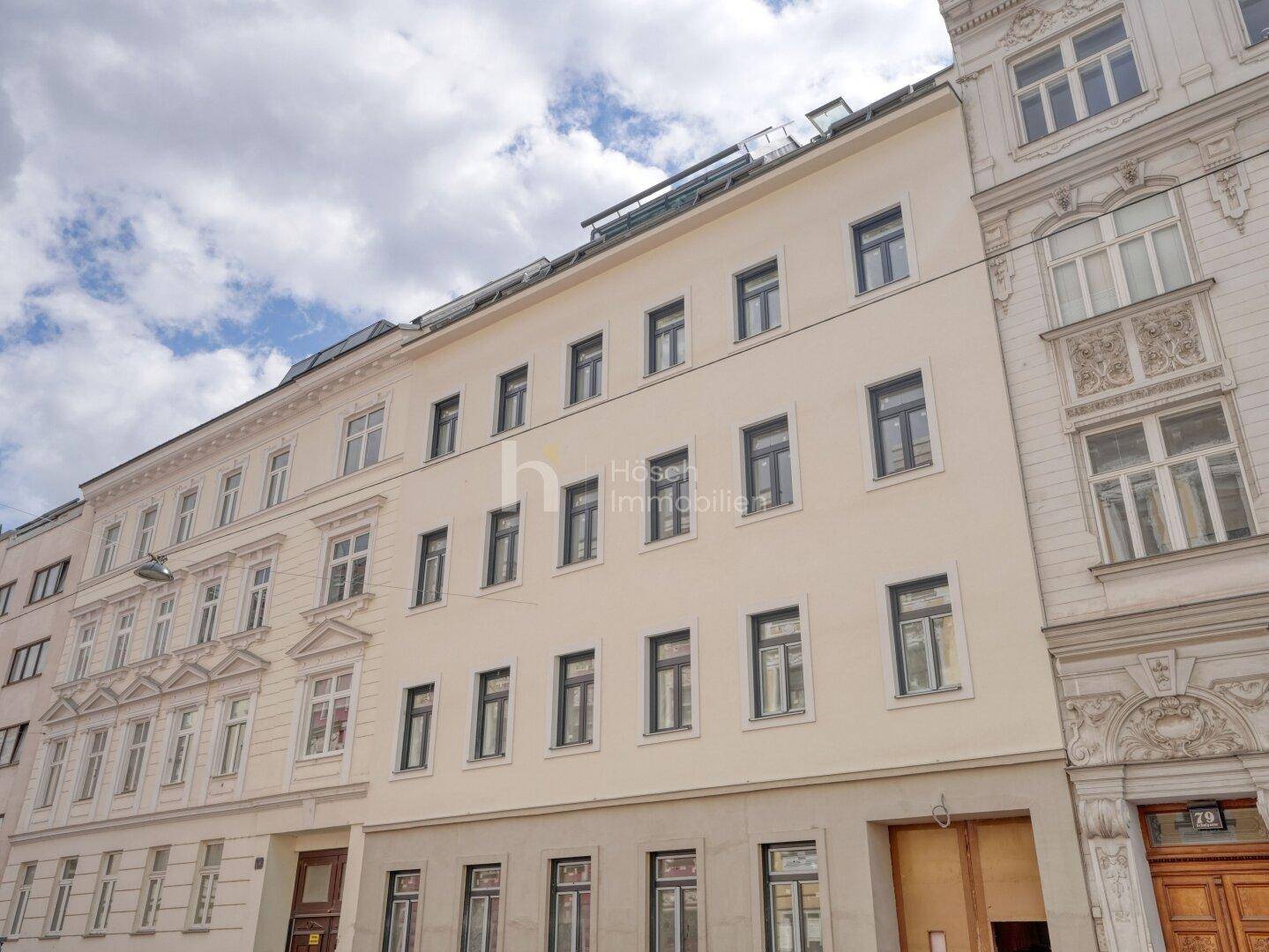 Historische Fassade eines Wohngebäudes mit vielen Fenstern und klassischer Architektur in der Stadt.