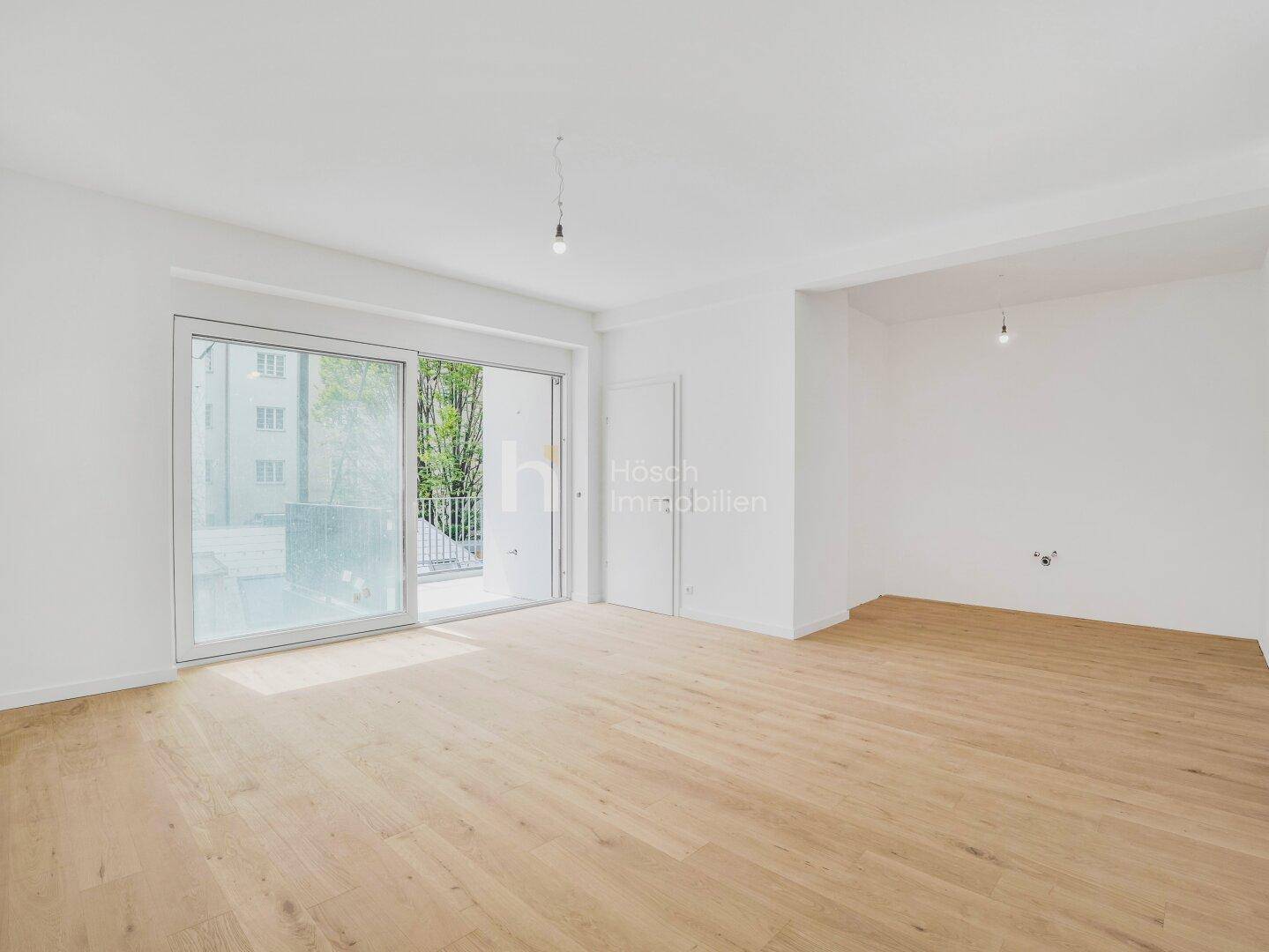Geräumiges, helles Zimmer mit Holzboden und Zugang zu einem Balkon oder einer Terrasse.