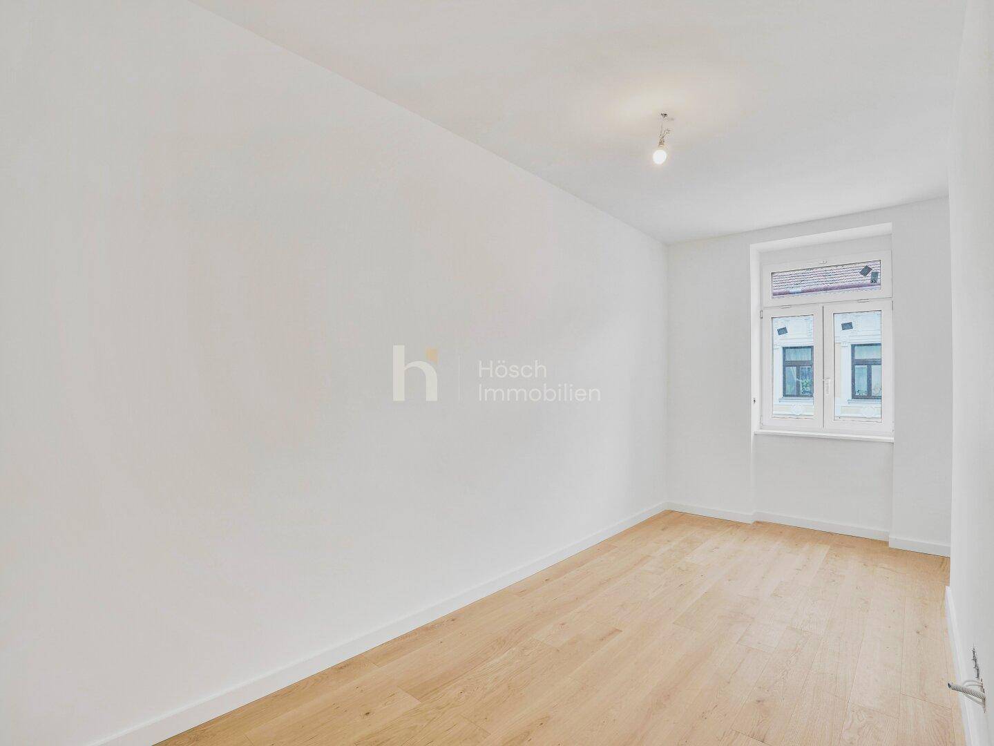 Ruhiges Zimmer mit Holzboden und einem Fenster, das eine angenehme Atmosphäre schafft.