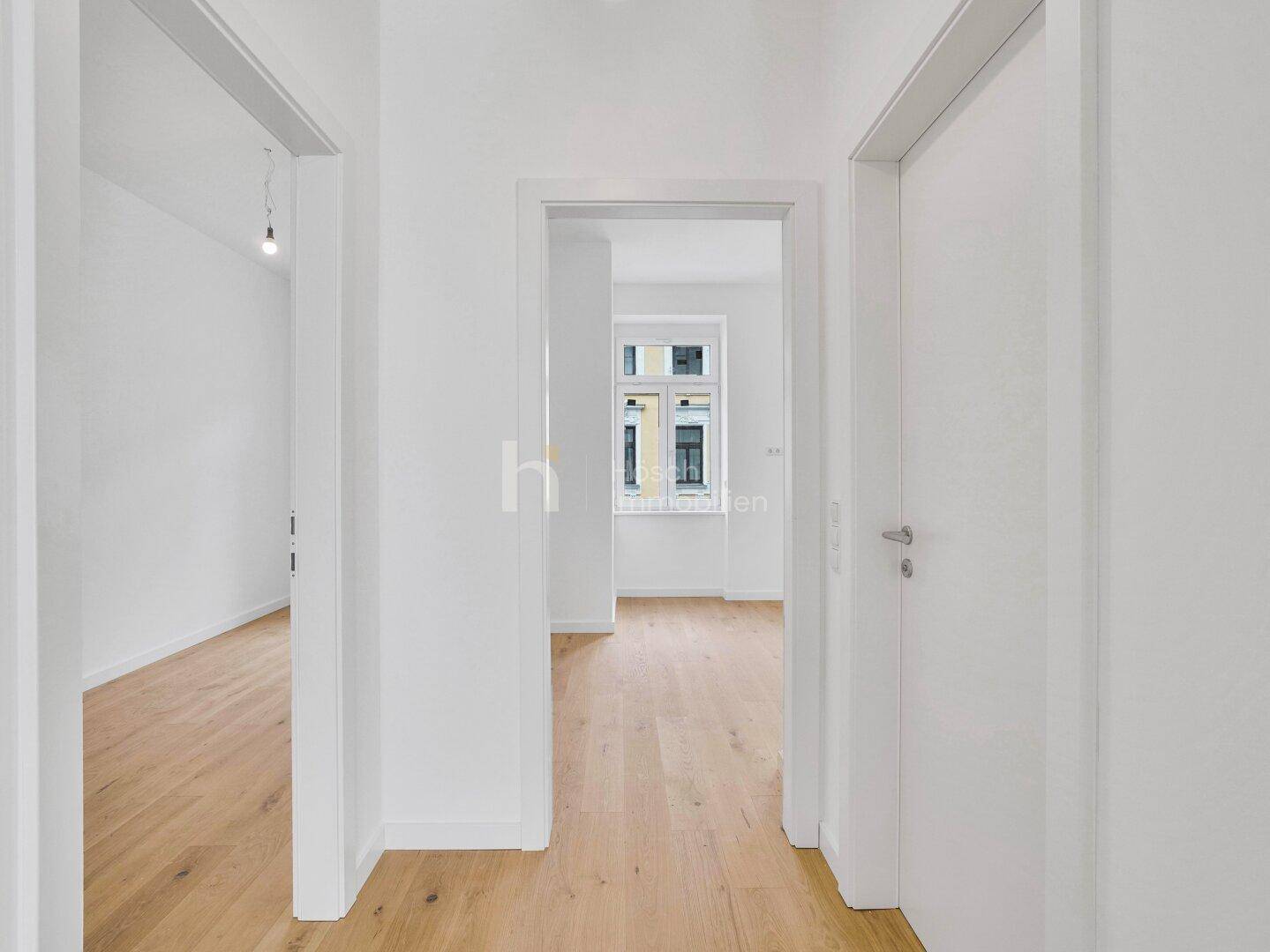 Heller Flur mit Holzboden, der zu verschiedenen Zimmern und einem Fenster am Ende führt.