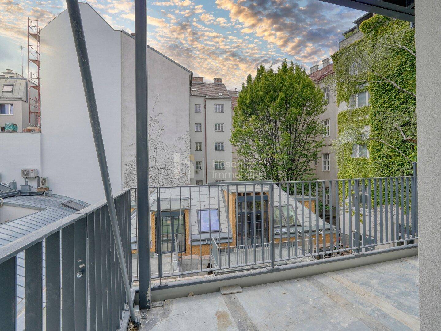 Blick von einem Balkon auf die umliegenden Gebäude und einen begrünten Innenhof.