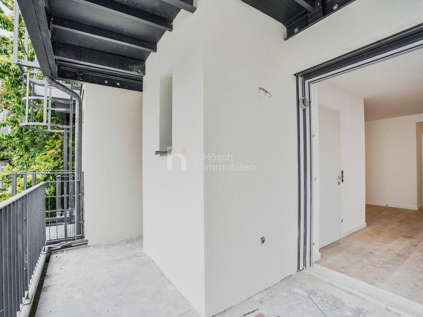 Zugang zu einem Balkon mit Blick auf die grüne Umgebung und den externen Aufzug.
