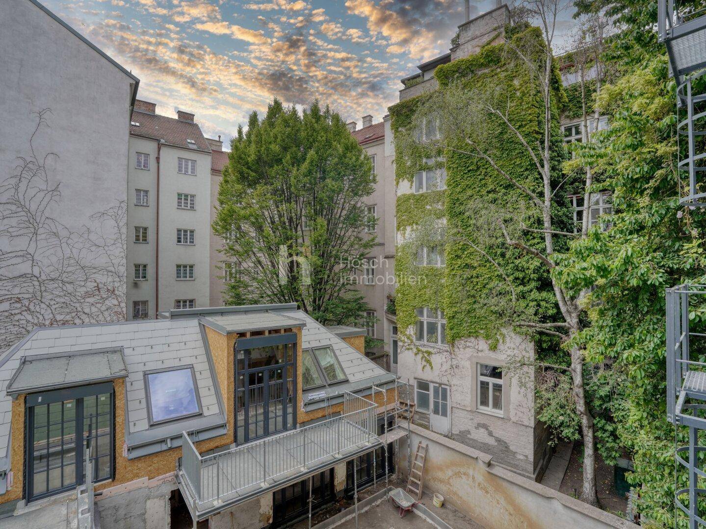 Blick auf den Innenhof mit Neubau-Anbau, Balkon und begrünten Fassaden.
