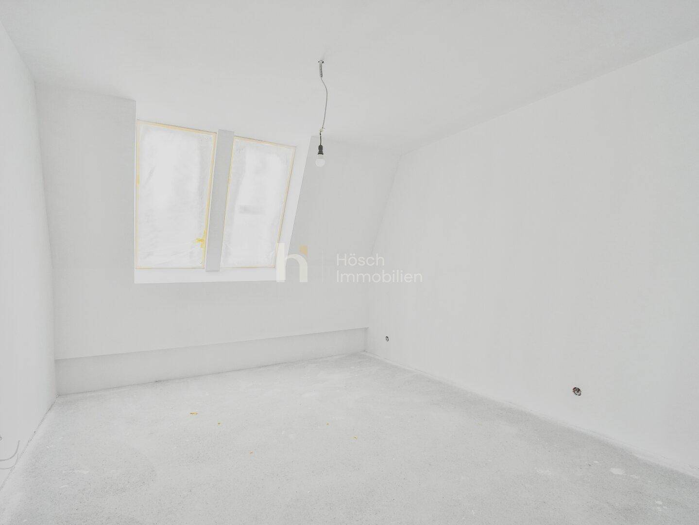 Helles, unmöbliertes Schlafzimmer mit Dachfenster und weiß gestrichenen Wänden.