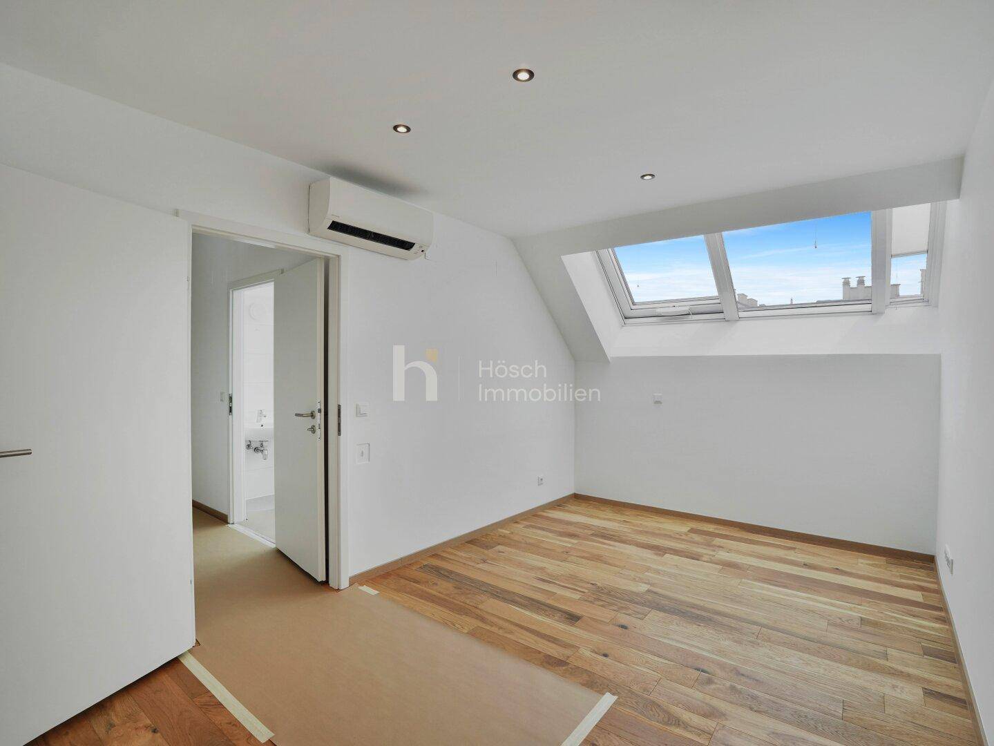Helles Schlafzimmer im Dachgeschoss mit Holzboden, Klimaanlage und Dachfenstern für viel Licht.