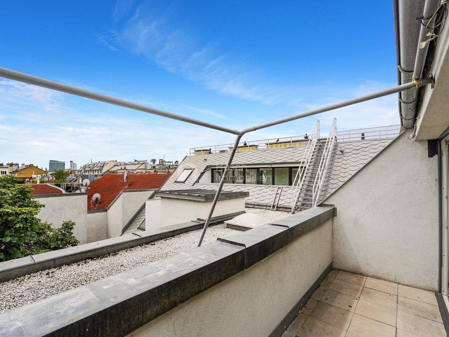Dachterrasse mit Kiesbelag und Treppenzugang, bietet weiten Blick über die Dächer der Stadt.
