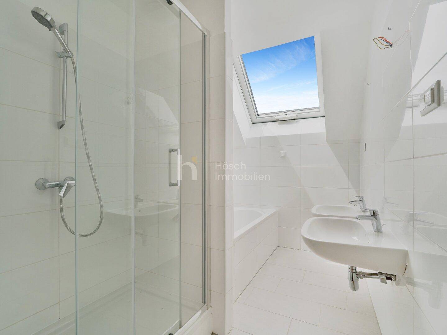 Modernes Badezimmer mit Duschkabine, Waschbecken und Dachfenster.