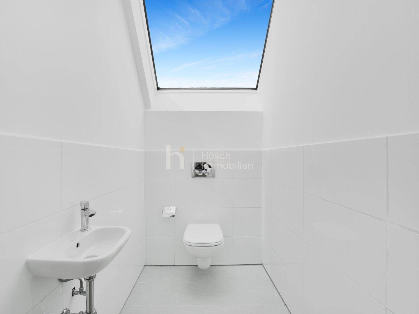 Modernes Gäste-WC mit wandhängender Toilette, kleinem Waschbecken und Oberlicht für Tageslicht.