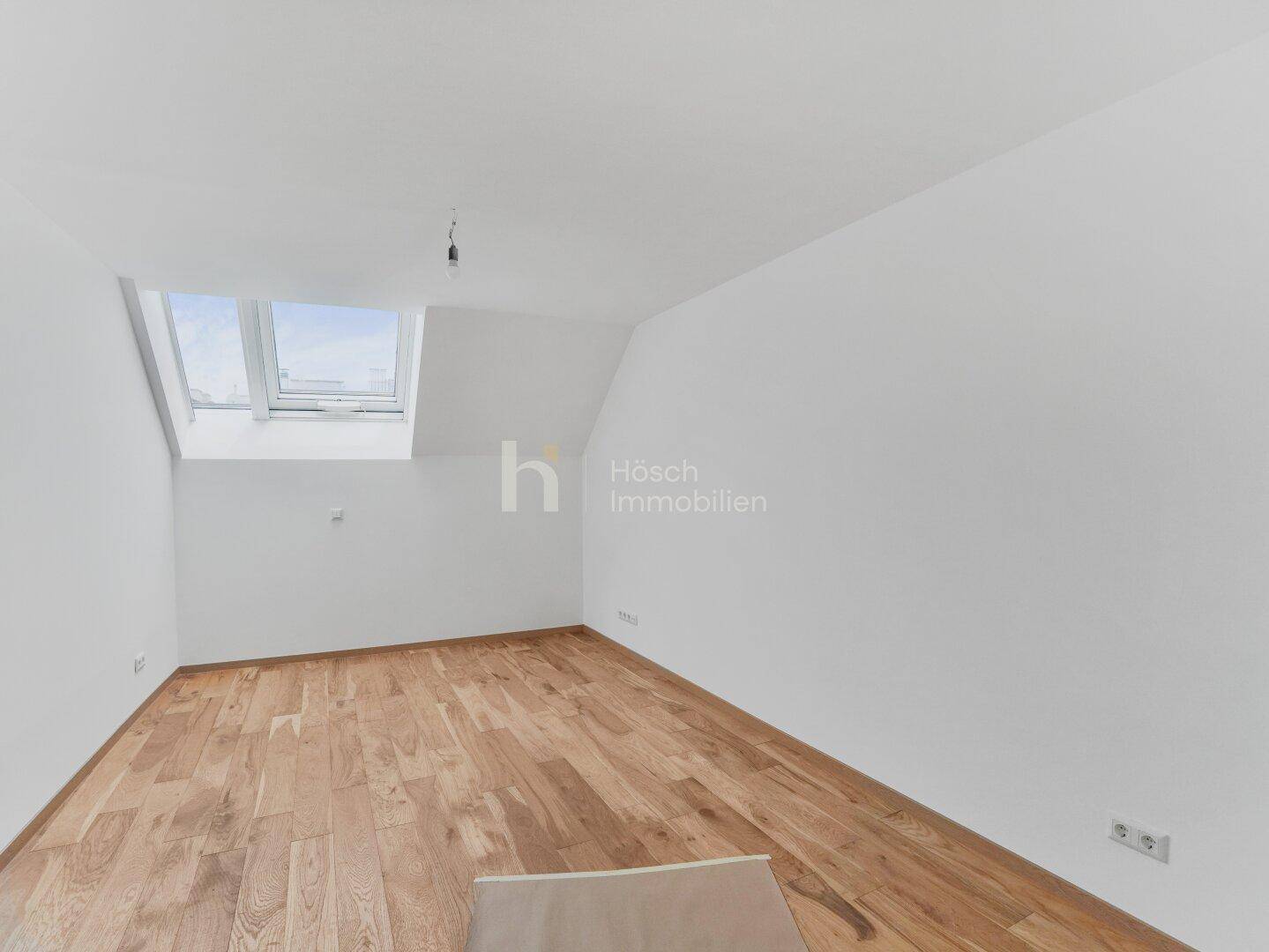 Helles Zimmer im Dachgeschoss mit Holzboden und Dachfenster, ideal als Schlaf- oder Arbeitszimmer.