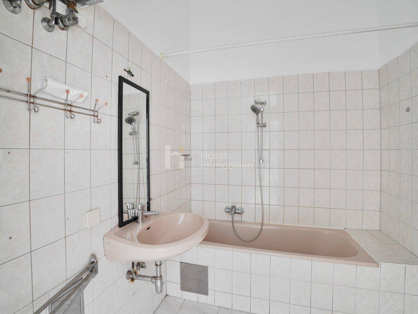 Badezimmer im 80er-Jahre-Stil mit rosa Badewanne, Waschbecken und weißen Fliesen.