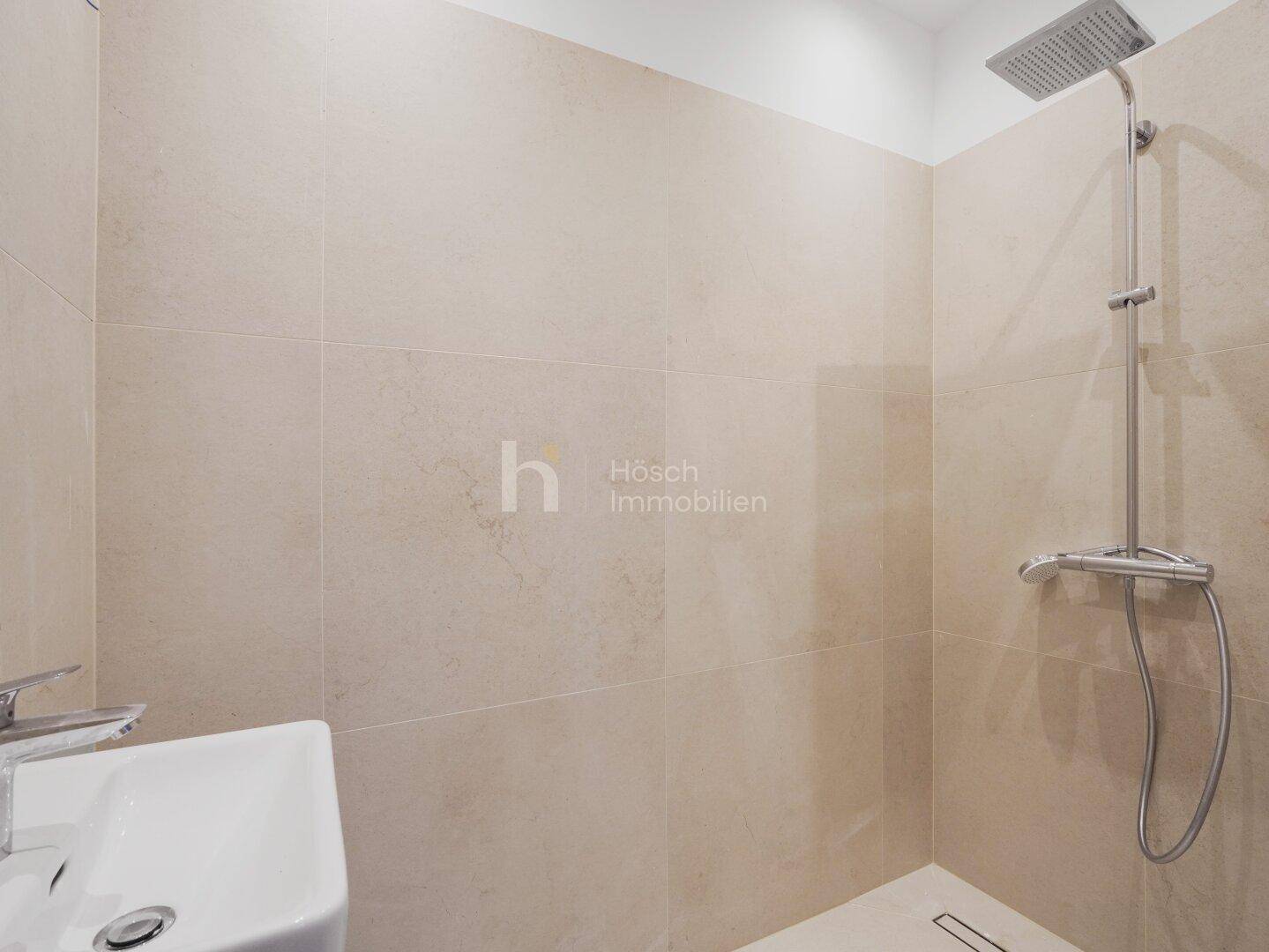 Modernes Badezimmer mit ebenerdiger Dusche, Regenduschkopf und beigefarbenen Fliesen.