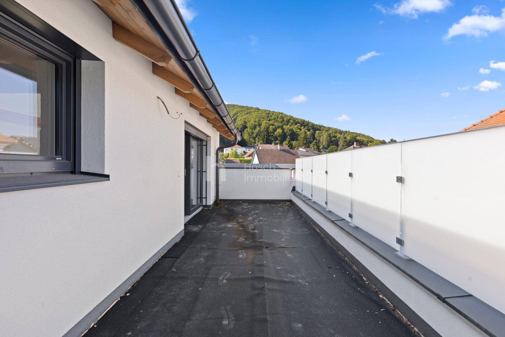 Geräumige Dachterrasse mit Blick auf die umliegende grüne Landschaft und Hügel.