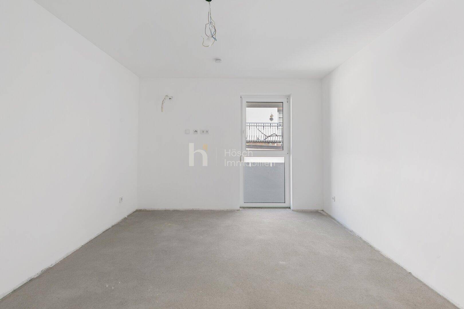 Unfertiges Schlafzimmer mit französischem Balkon und Rohbau-Boden in einem Neubau.
