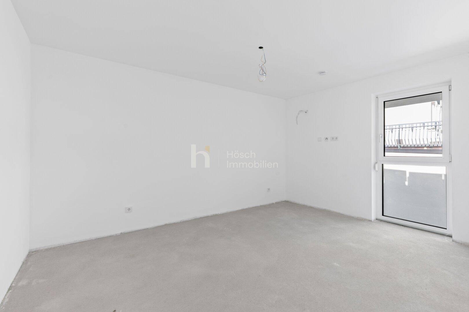 Geräumiges, unfertiges Schlafzimmer mit französischem Balkon und Rohbau-Boden.