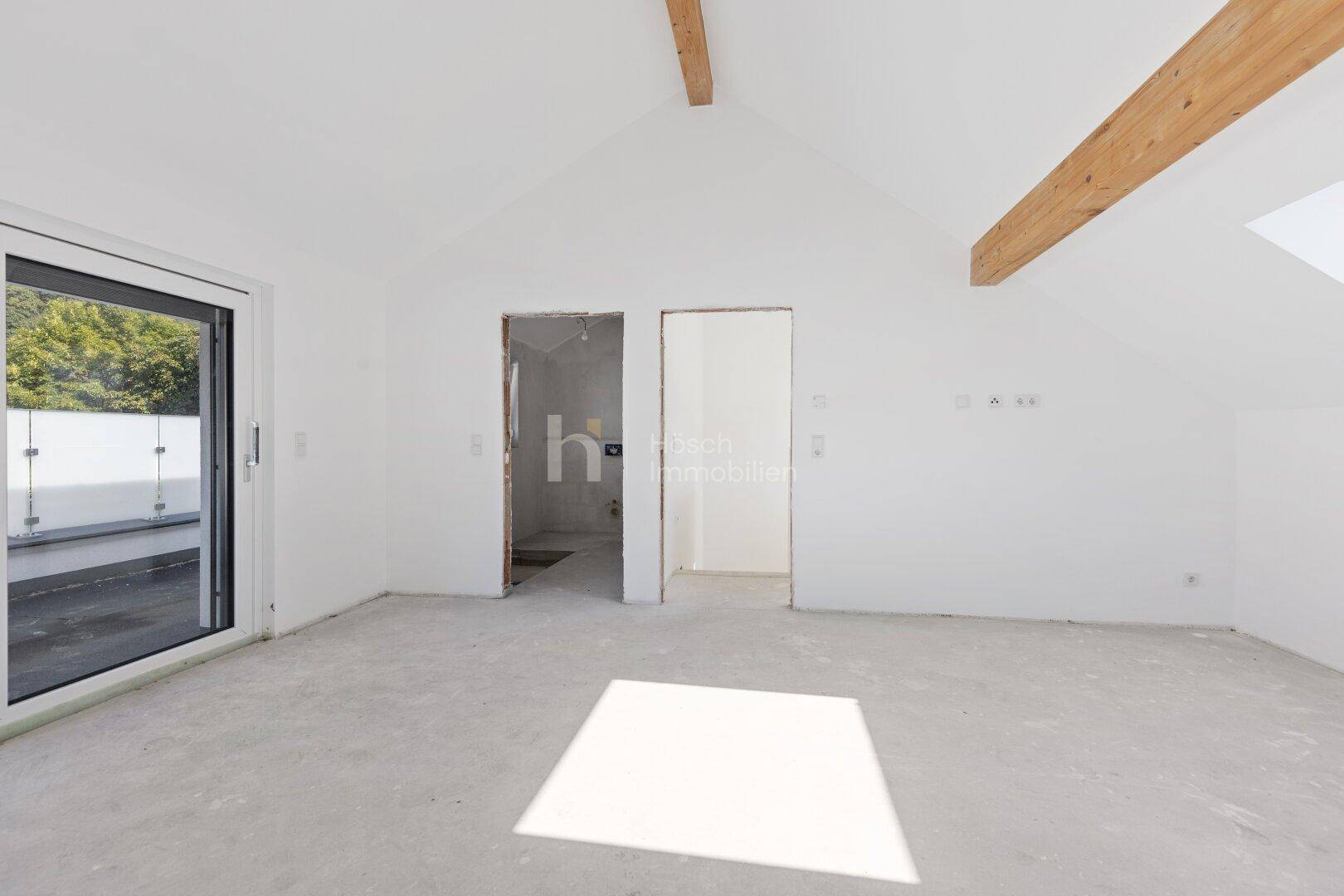 Unfertiger Dachbodenraum mit sichtbaren Holzbalken, Türöffnungen und Rohbau-Boden.