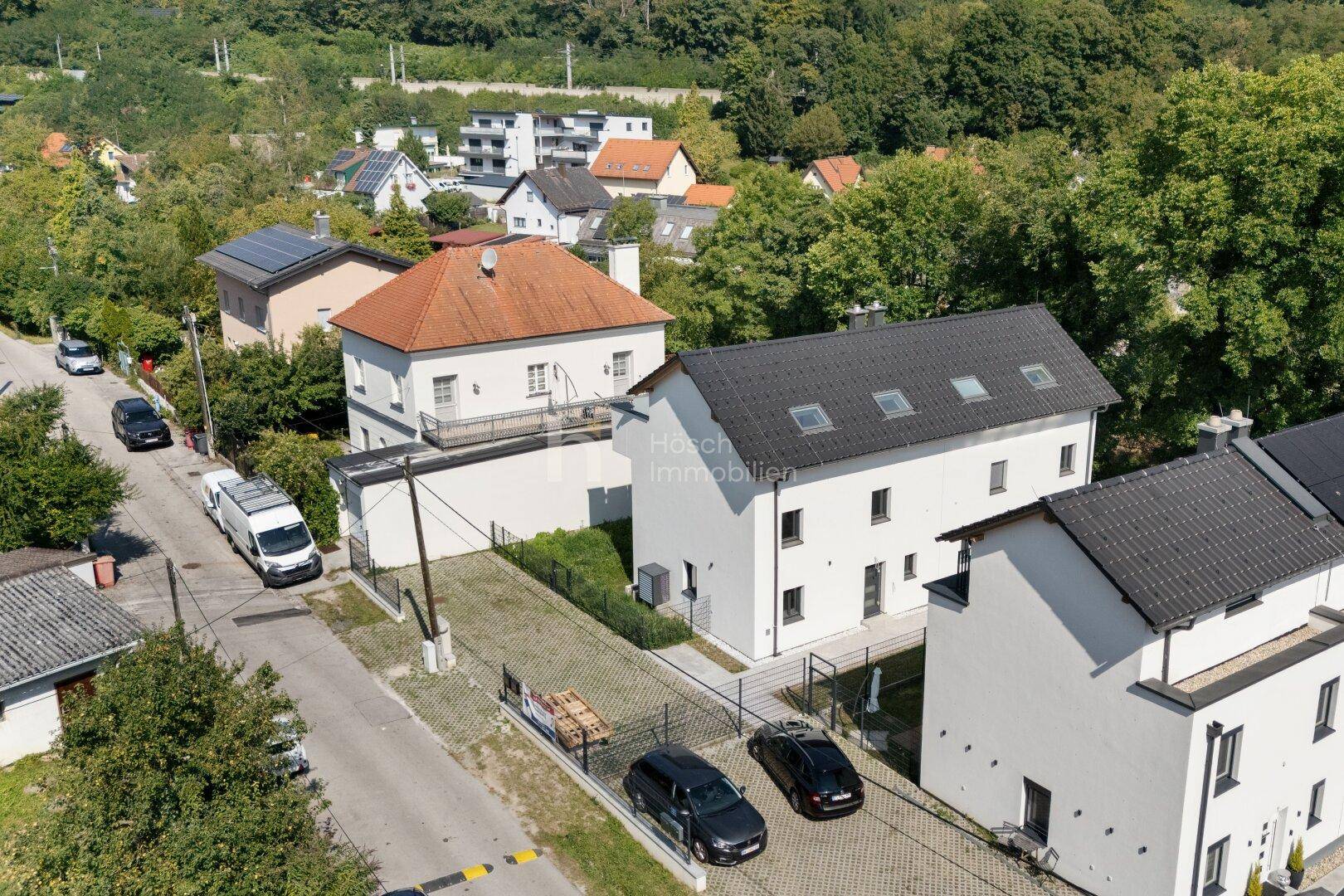 Luftaufnahme einer Wohnsiedlung mit modernen Häusern und umliegender grüner Landschaft.