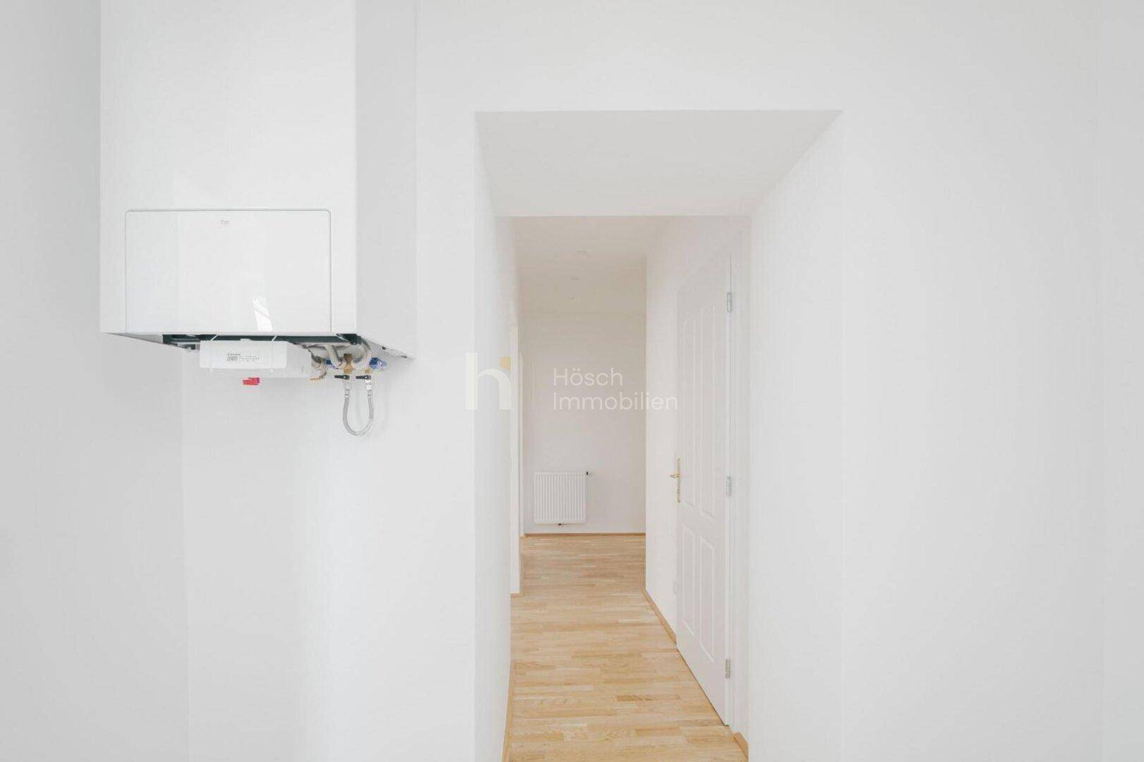 Flur mit einem Heizkessel an der Wand und Zugang zu weiteren Räumen.