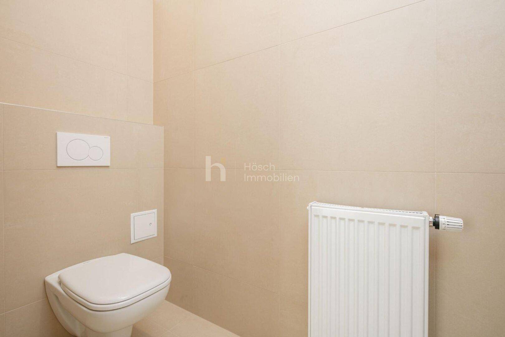 Modernes WC mit beigefarbenen Fliesen, wandhängender Toilette und Heizkörper.