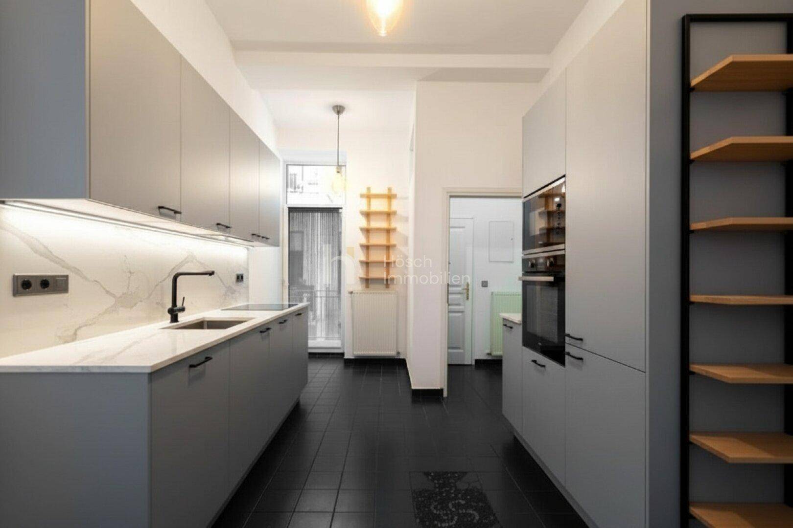 Moderne Küche mit grauen Schränken, Marmor-Arbeitsplatte, dunklem Fliesenboden und Einbaugeräten.
