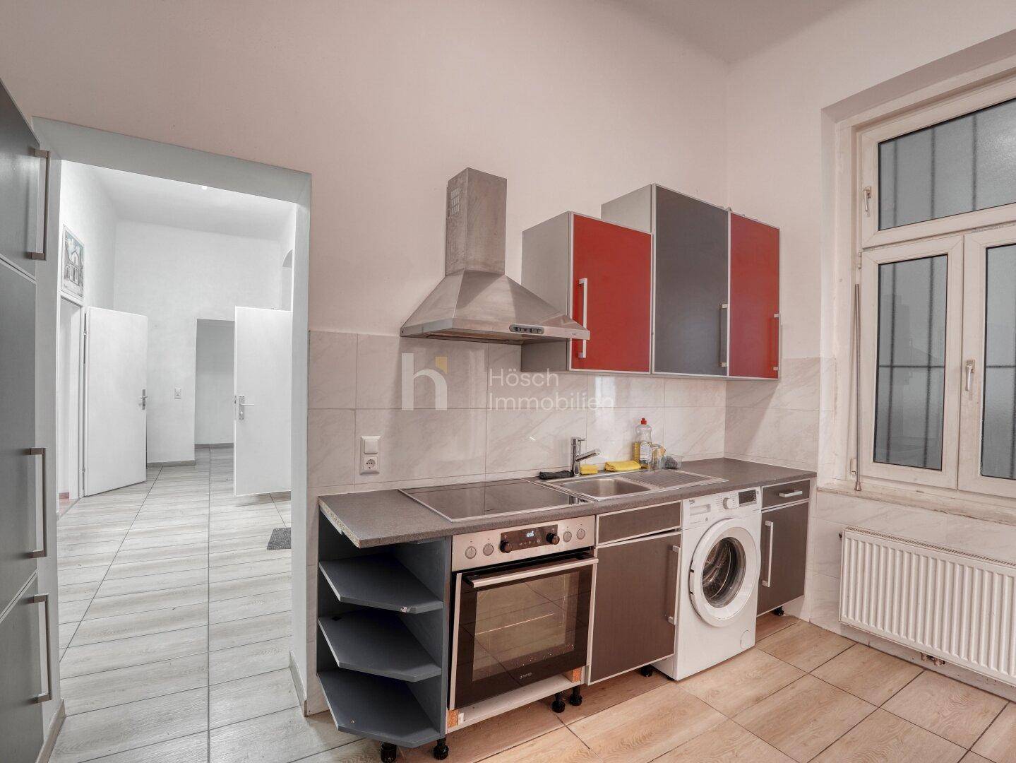 Funktionale Küche mit modernen Schränken, Herd, Backofen und Waschmaschine.