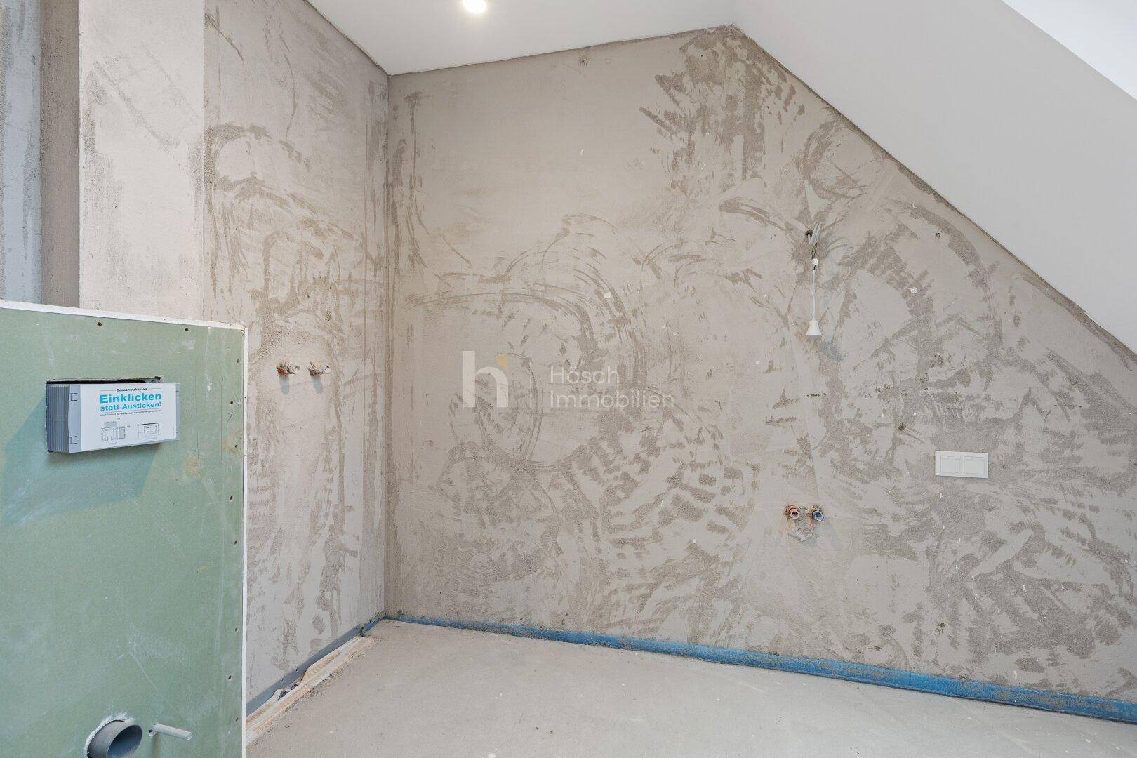 Unfertiges Badezimmer im Dachgeschoss mit schräger Wand und Anschlüssen.