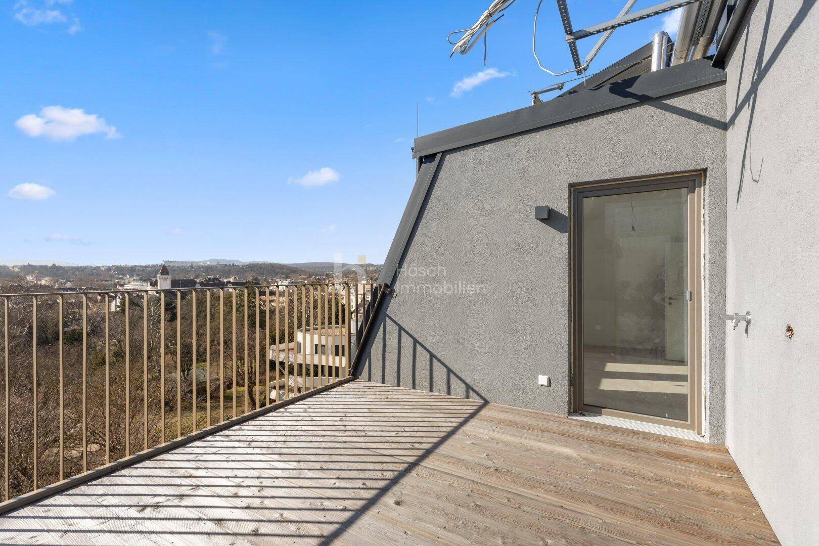 Dachterrasse mit Holzboden und weitem Blick über die Stadt und die hügelige Landschaft.