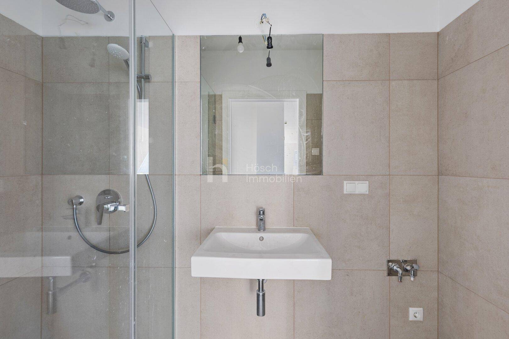 Modernes Badezimmer mit beigefarbenen Fliesen, Duschkabine und Einzelwaschbecken.