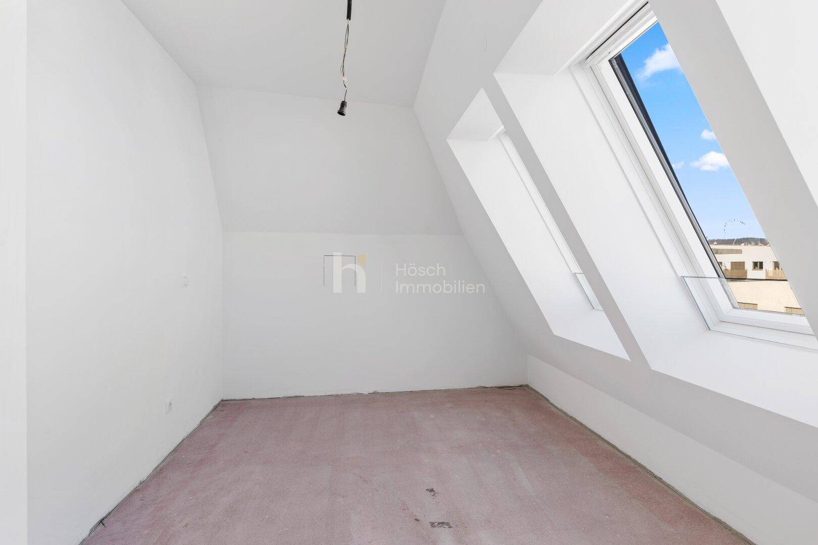 Helles Schlafzimmer im Dachgeschoss mit Dachfenstern und Rohbauzustand.