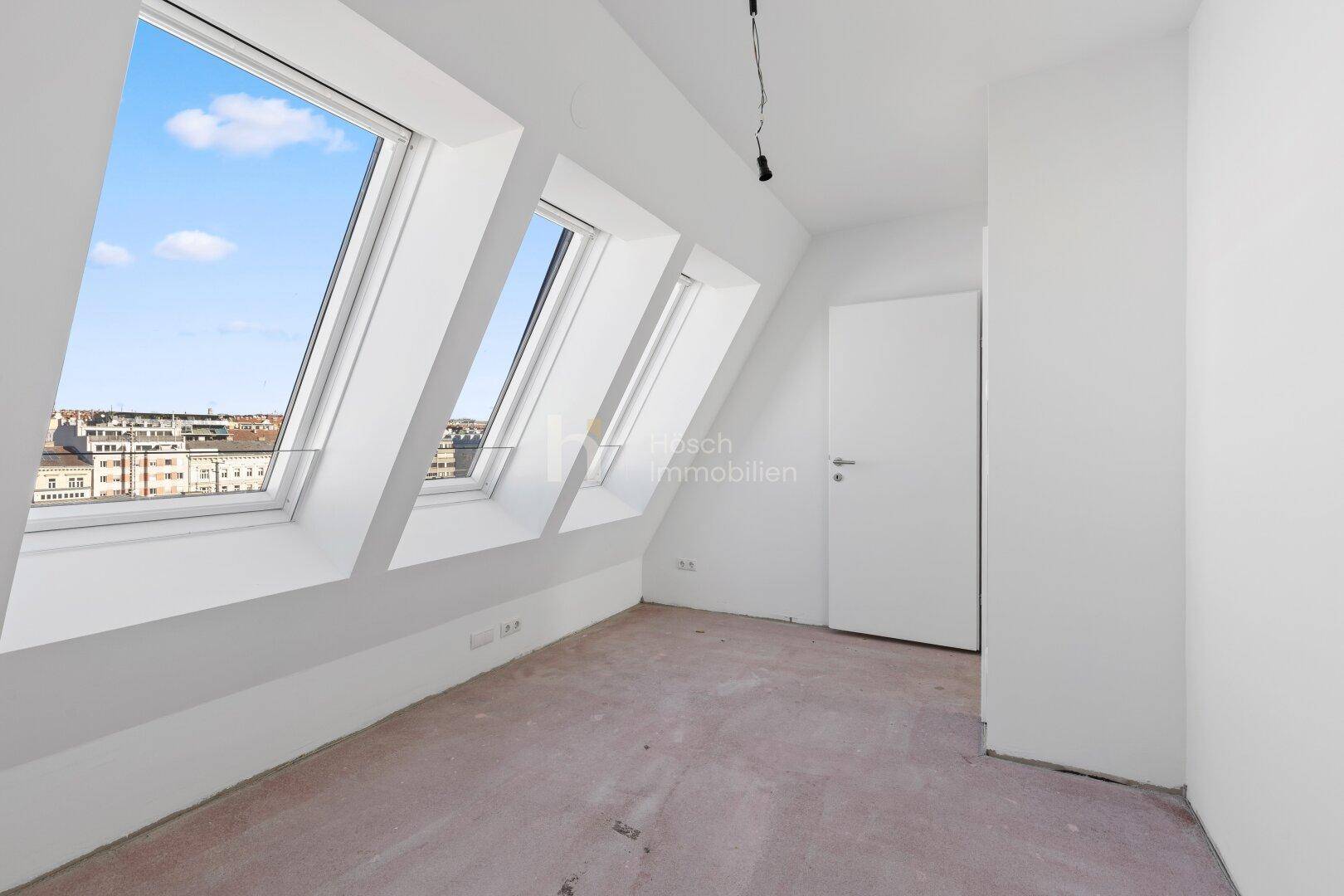 Geräumiges Schlafzimmer im Dachgeschoss mit mehreren Dachfenstern und Stadtblick.