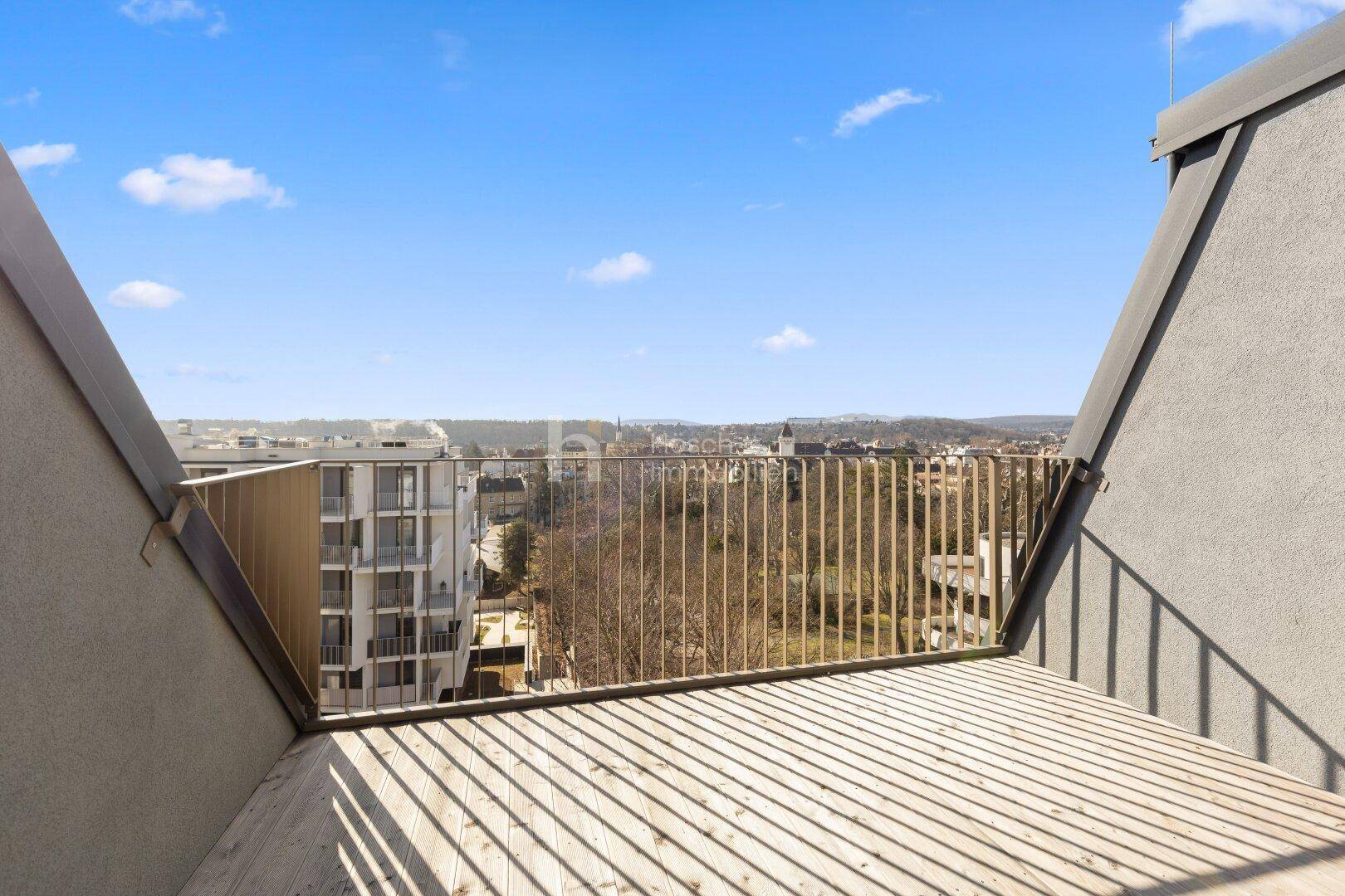 Dachterrasse mit Holzboden und weitem Blick über die Stadt und die umliegende Landschaft.