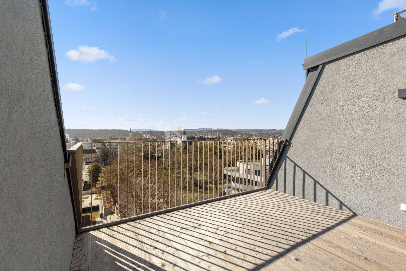 Geräumiger Balkon mit Holzboden und weitem Blick über die Stadt und Umgebung.