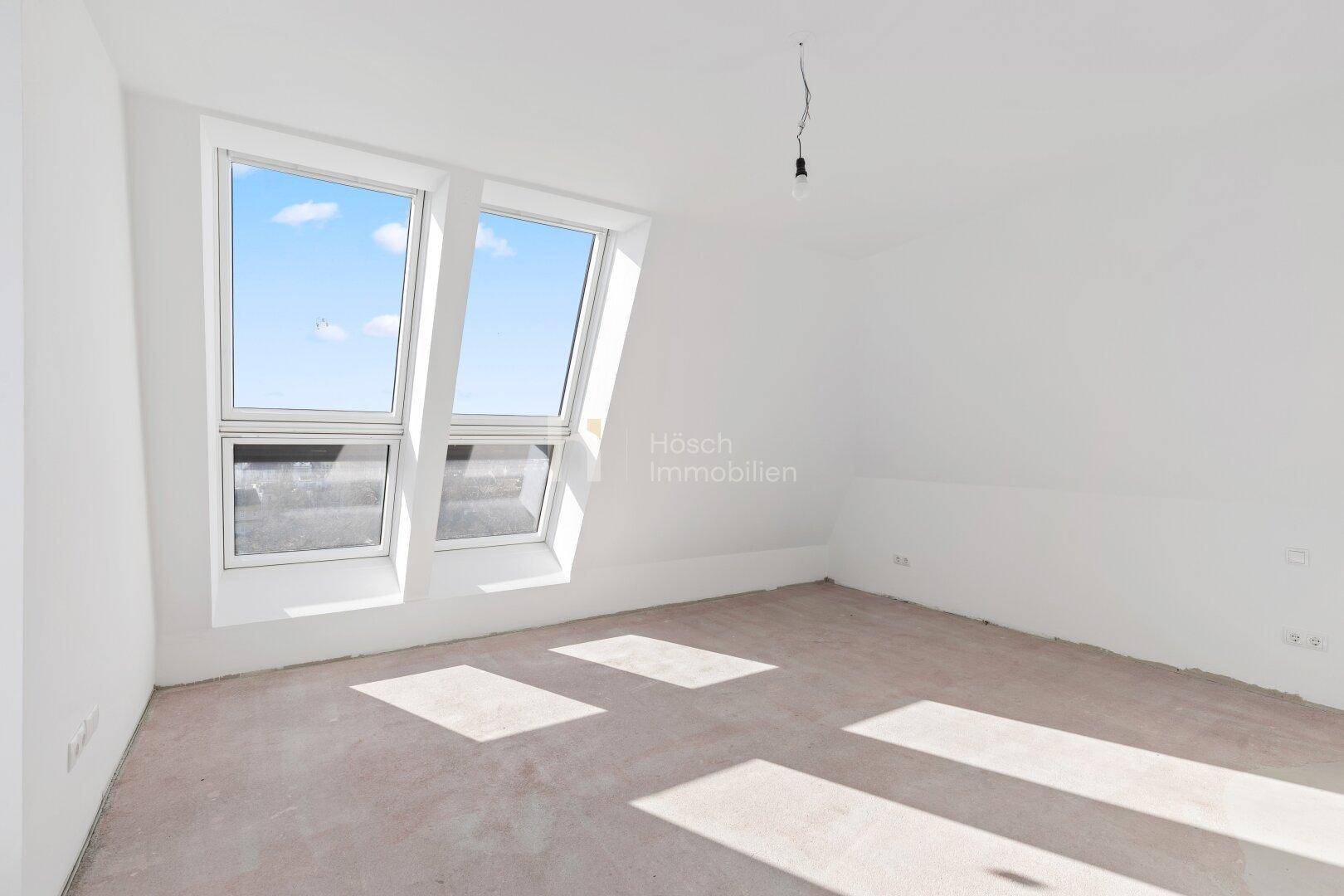 Helles Schlafzimmer im Dachgeschoss mit zwei großen Dachfenstern und Rohbauzustand.