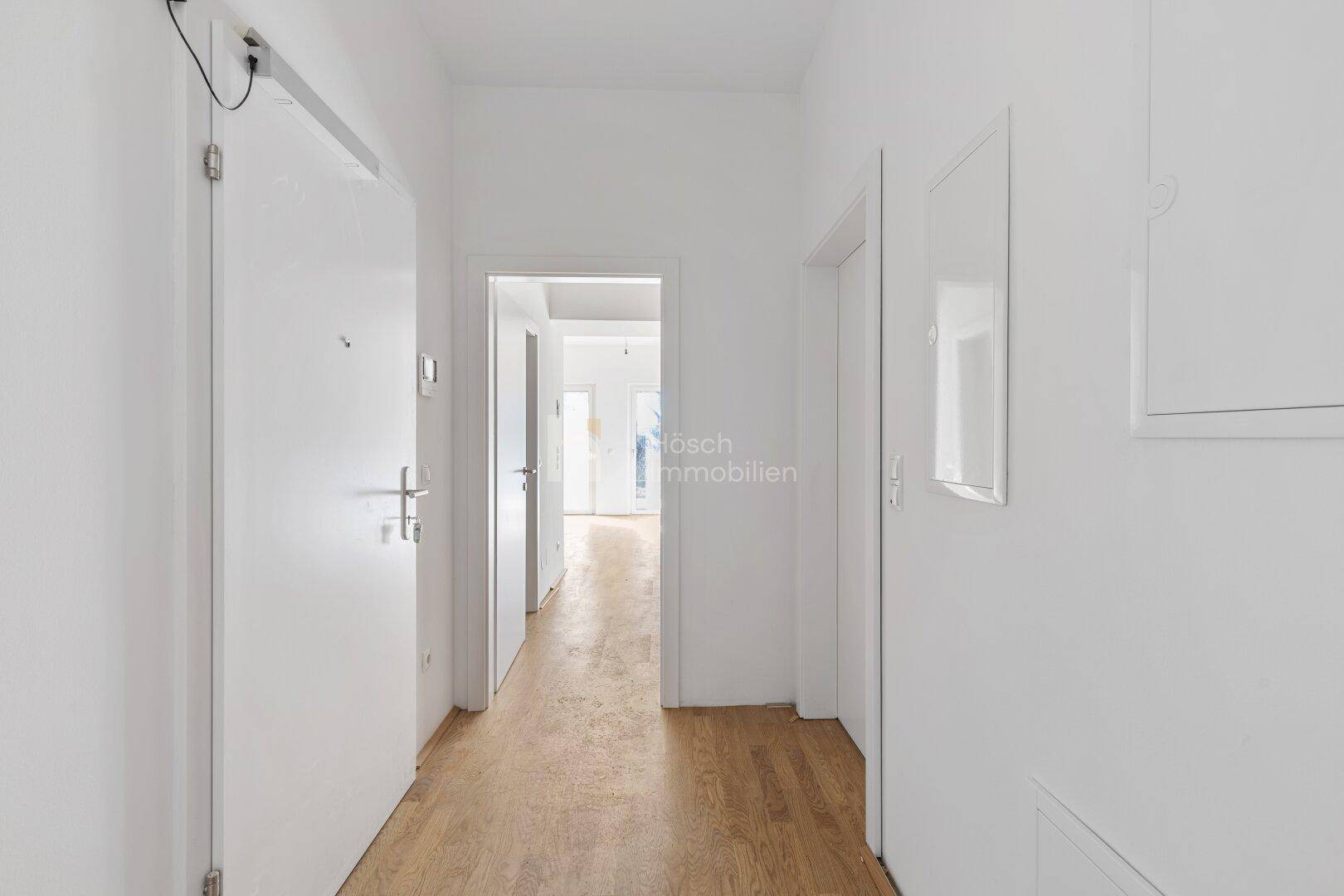 Heller Flur mit Holzboden und mehreren Türen, die zu den angrenzenden Räumen führen.