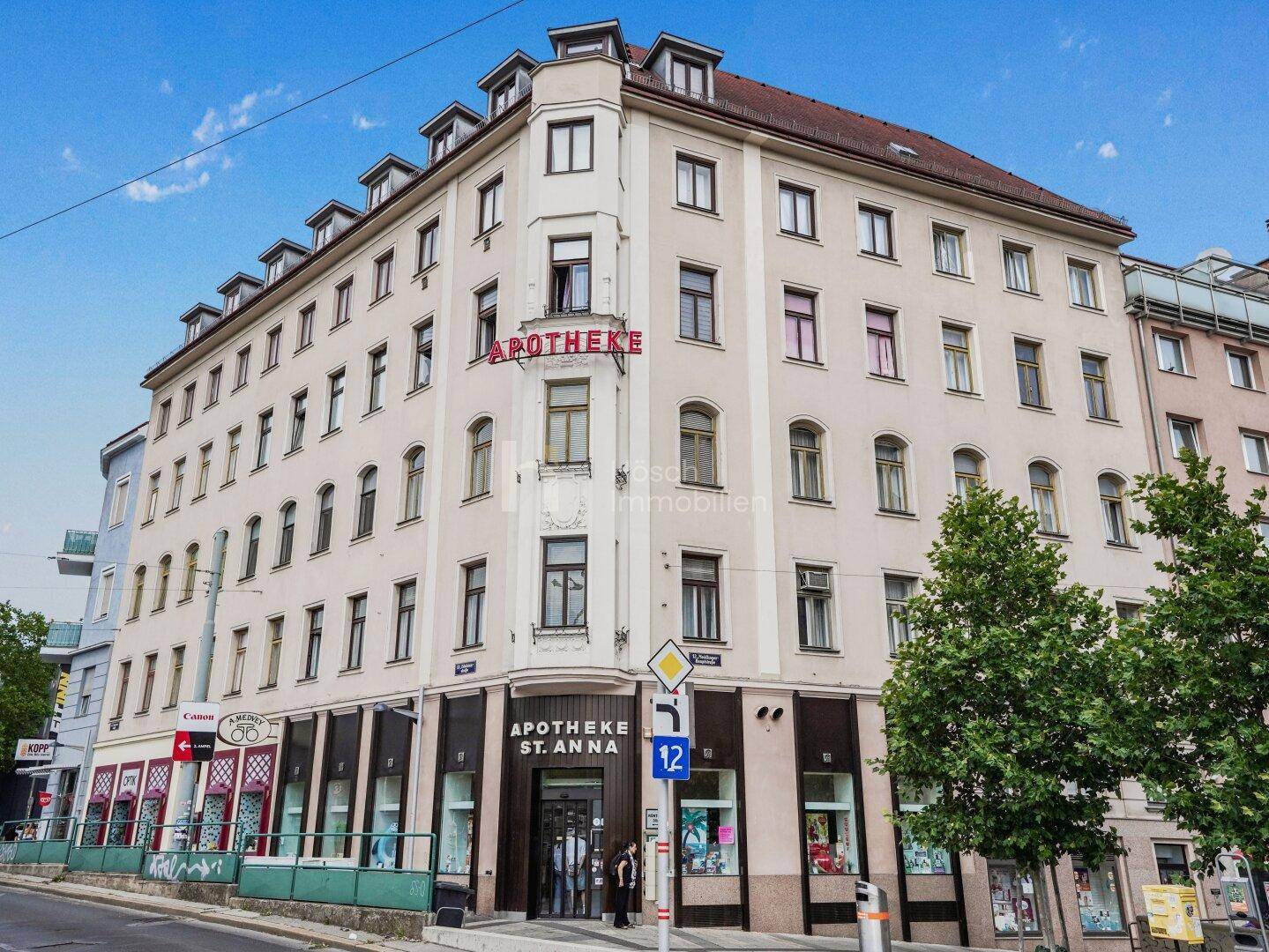 Historisches Eckgebäude mit Apotheke im Erdgeschoss und vielen Fenstern.