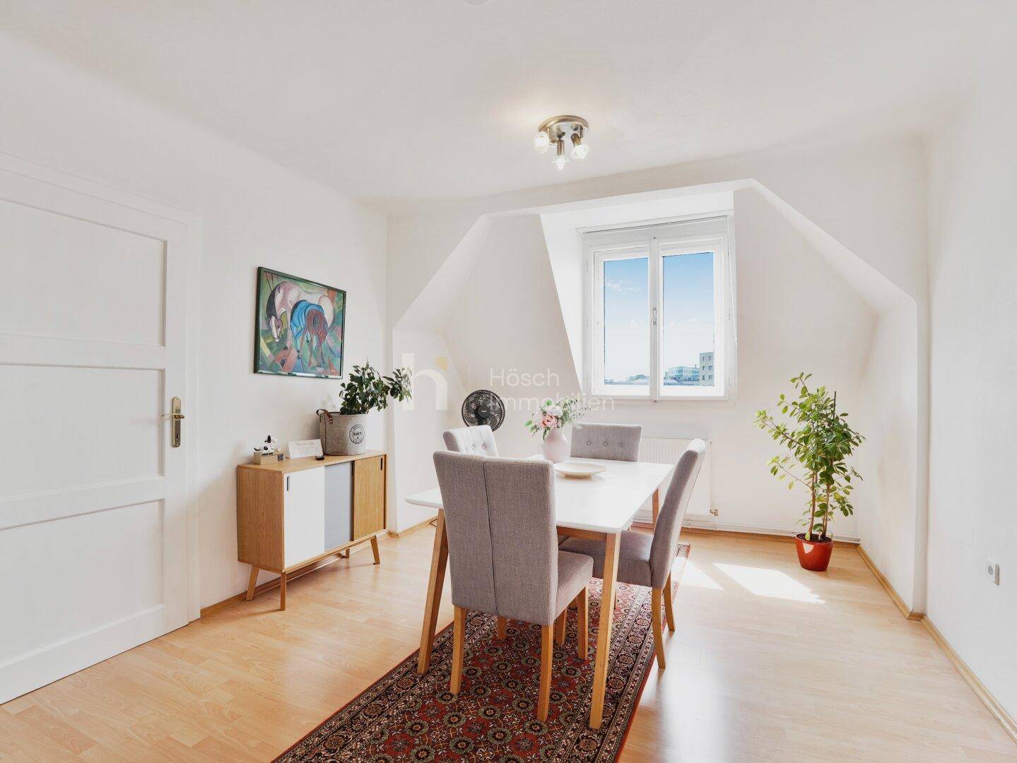 Helles Esszimmer mit Holzboden, modernem Esstisch und Blick aus dem Fenster.