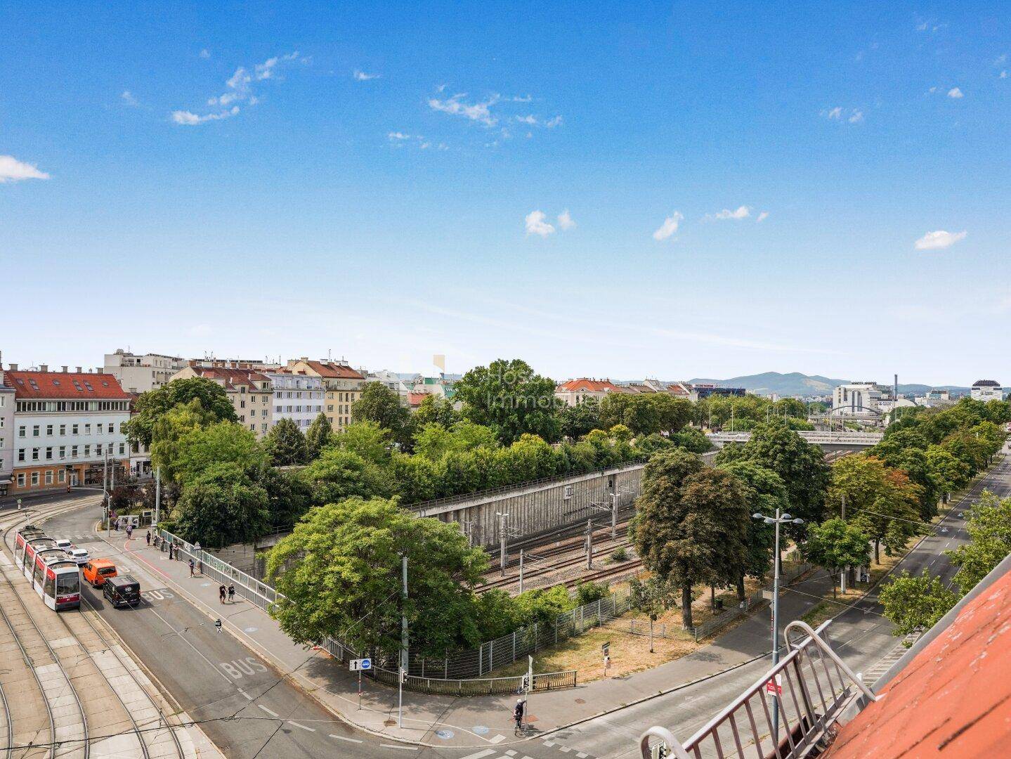 Panoramablick über die Stadt mit Straßenbahnen, viel Grün und urbaner Landschaft.