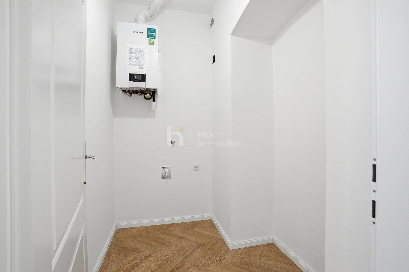 Praktischer Hauswirtschaftsraum mit Gastherme und Fischgrätparkett, ideal für Technik und Lagerung.