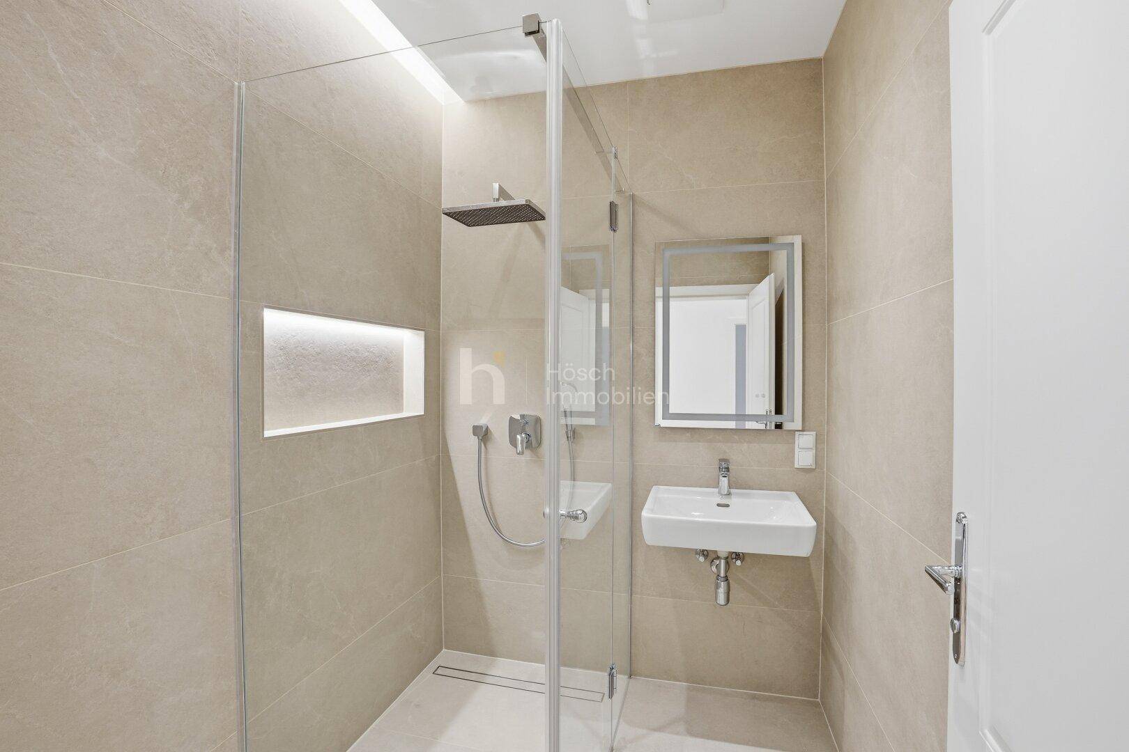 Elegantes Badezimmer mit großformatigen Fliesen, moderner Dusche und stilvollem Waschtisch.