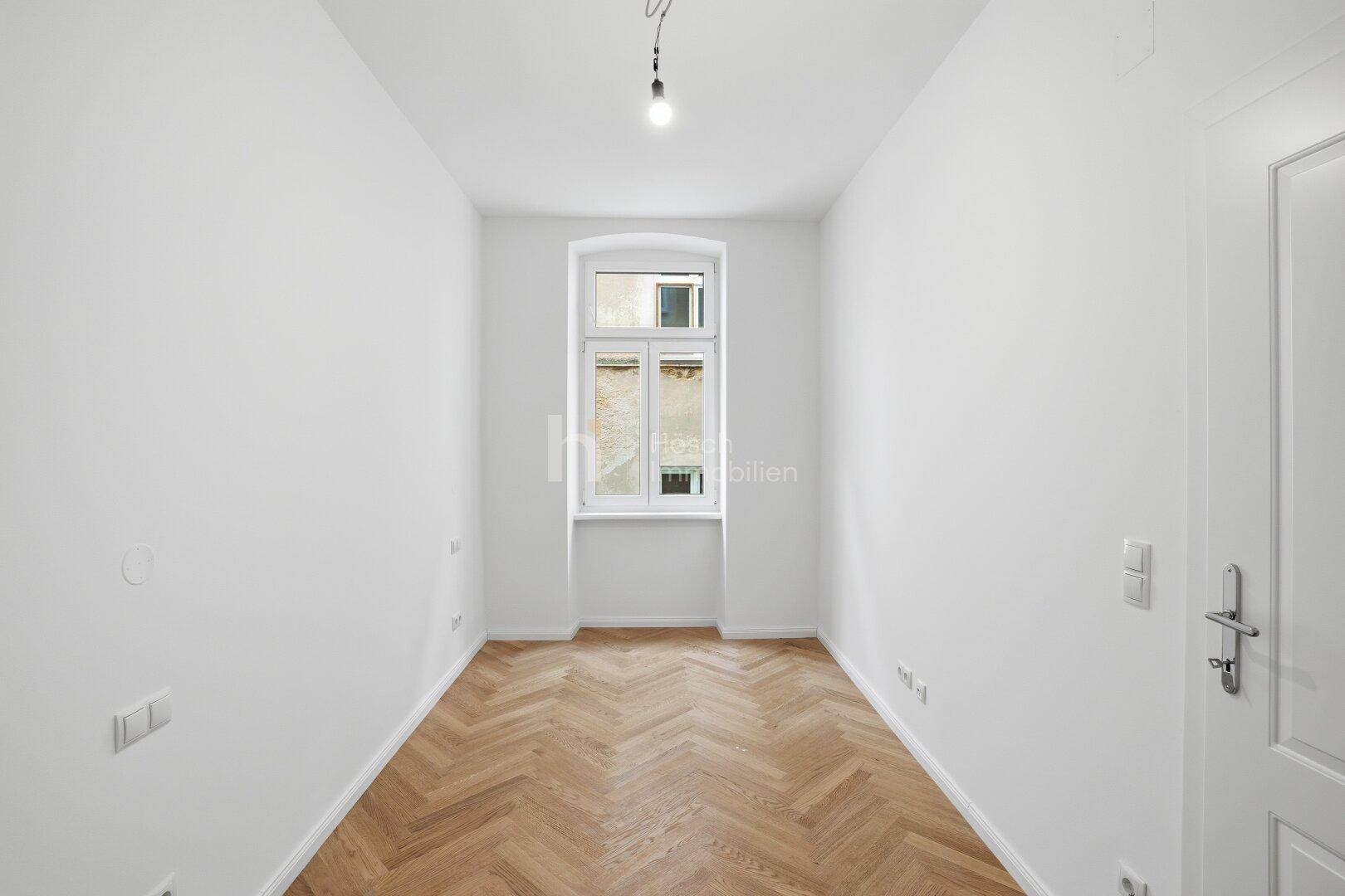 Helles, schmales Zimmer mit Fischgrätparkett und einem Fenster, vielseitig nutzbar.