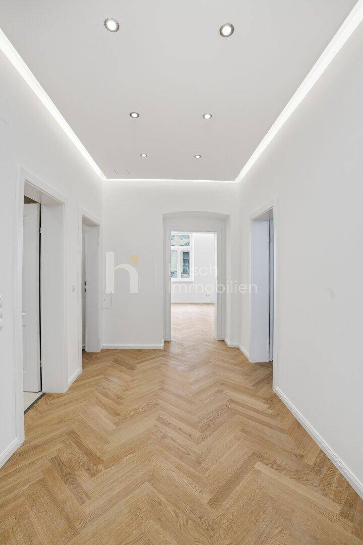 Langer, lichtdurchfluteter Flur mit elegantem Fischgrätparkett und moderner Einbauleuchten.