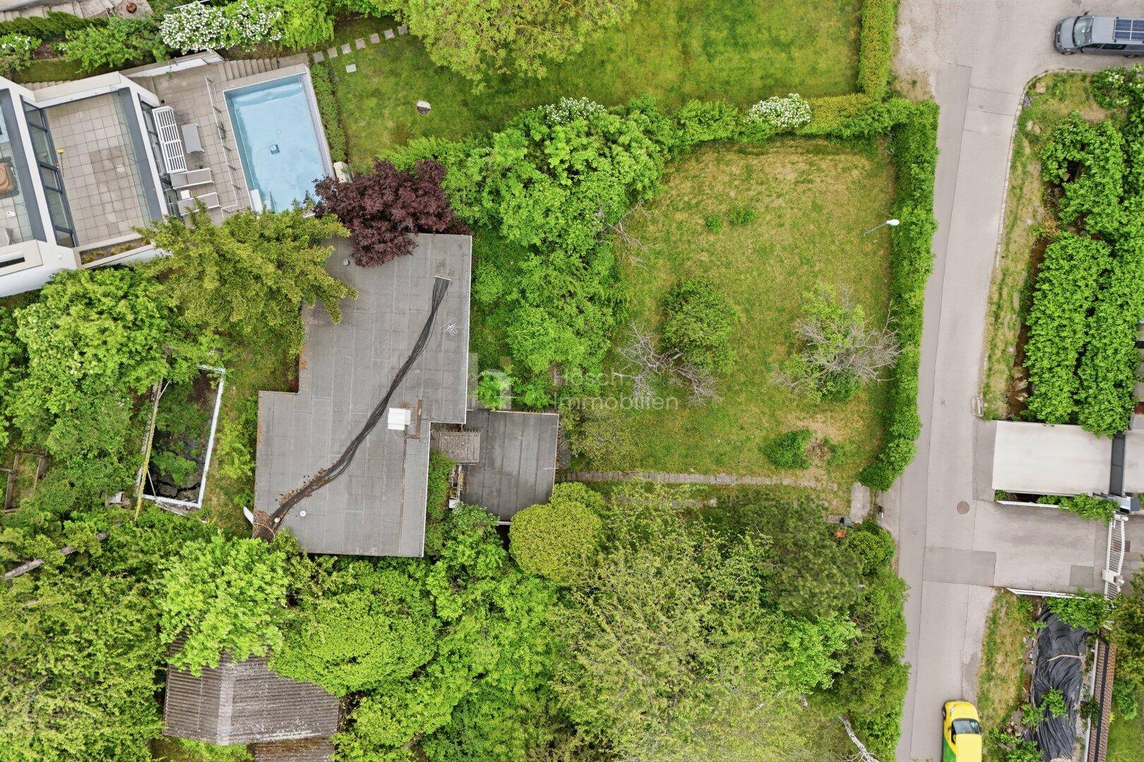 Draufsicht auf das Haus mit Flachdach und den umliegenden Grundstücken, inklusive Nachbarpool.