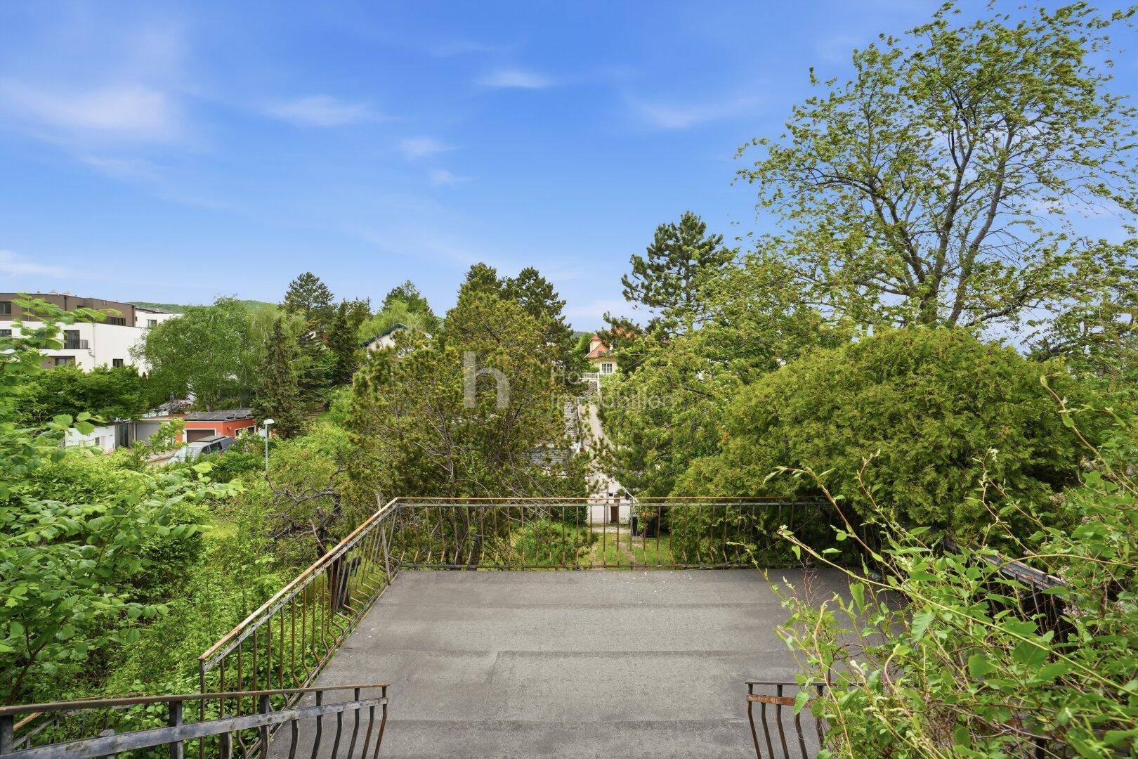 Geräumige Terrasse mit Blick über grüne Bäume und die umliegende Wohnbebauung.