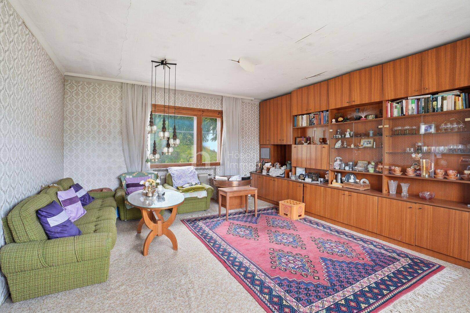 Gemütliches Wohnzimmer im Vintage-Stil mit Holzschrankwand, gemusterter Tapete und Teppich.